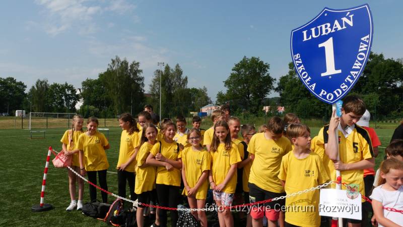 dzieci w żółtych koszulkach z tablicą na kiju z napisem "Lubań, Szkoła podstawowa nr 1"